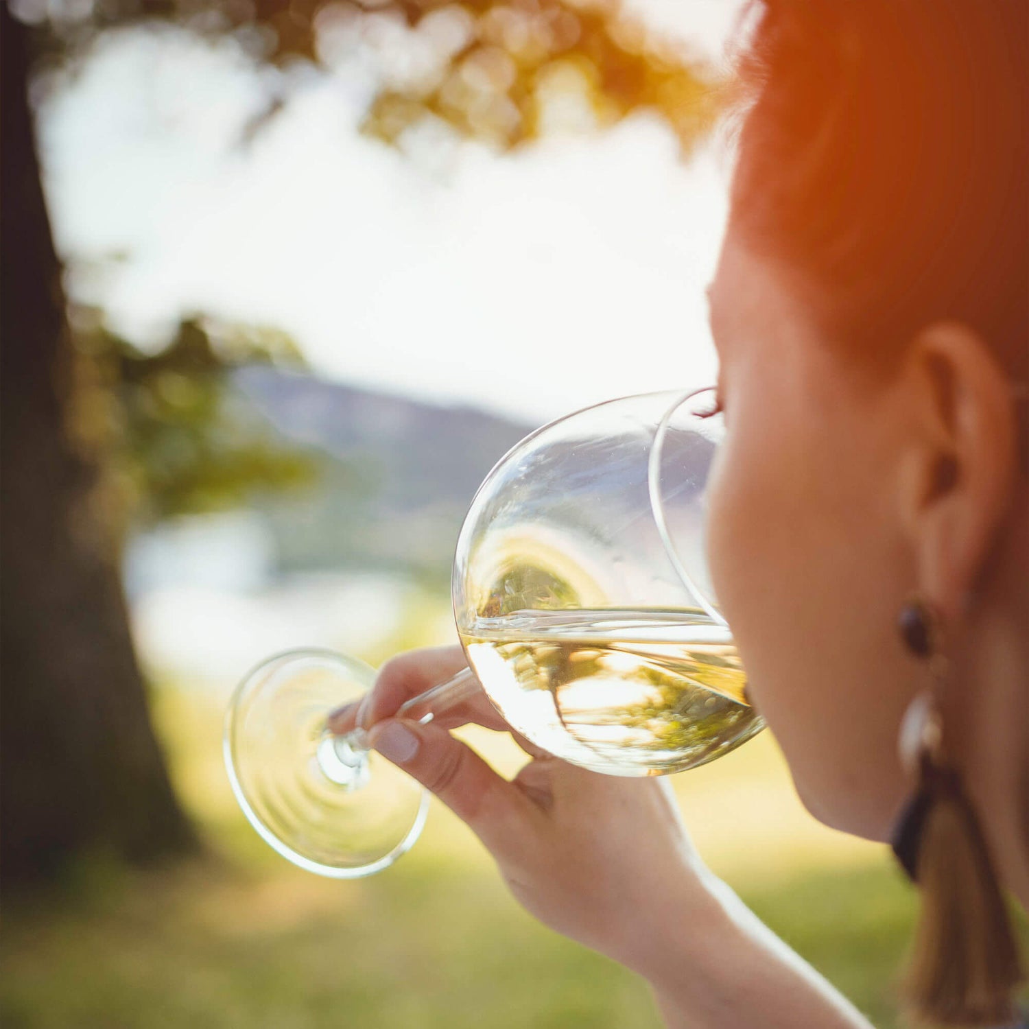 Eine Frau die in der Natur ein Glas Weißwein genießt