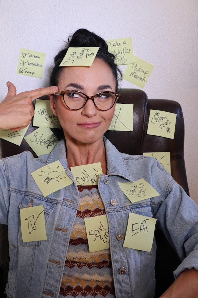 Junge schwarzhaarige Frau mit Brille und vielen Post-it Zetteln um sich herum