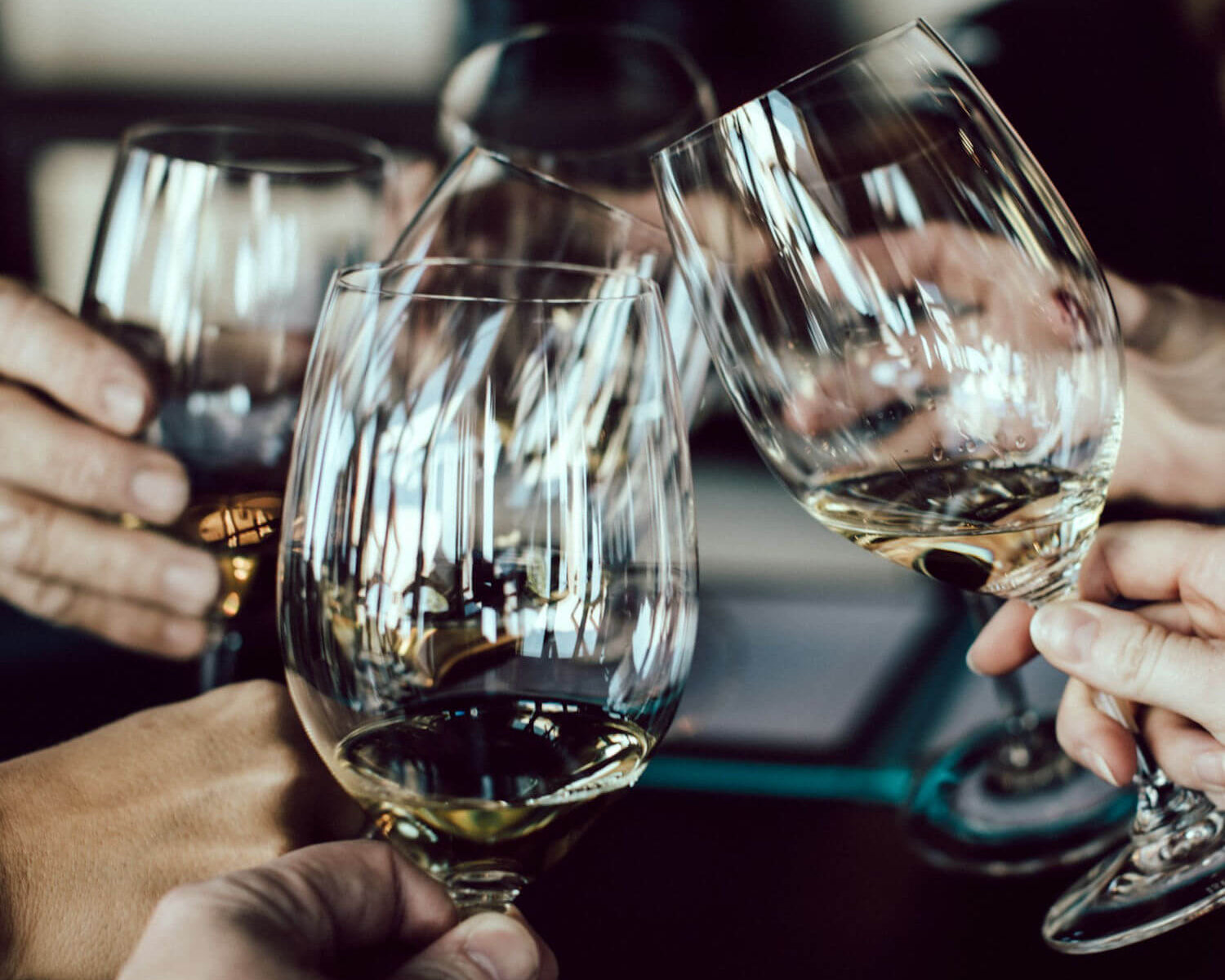 Eine Gruppe von Weingläsern gefüllt mit Weißwein, die angestoßen werden